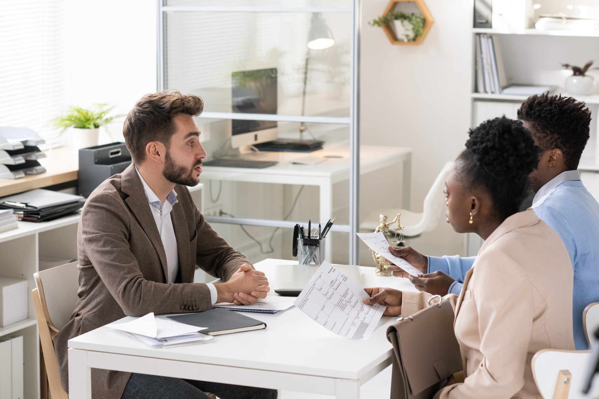 Young contemporary lawyer consulting African couple